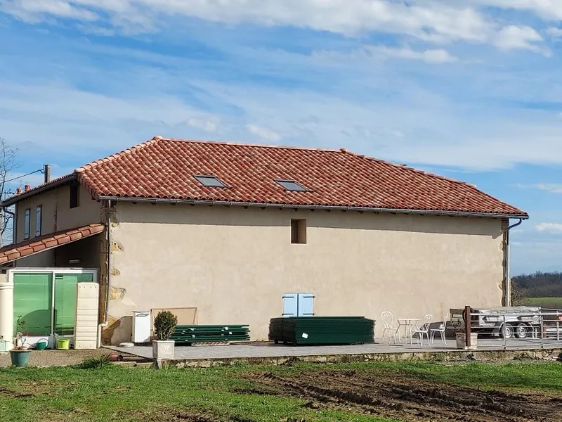 Grange en pierre avec toiture en tuiles et volets verts